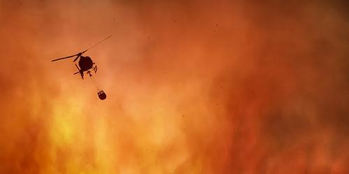 Helicopter flies over forest fire